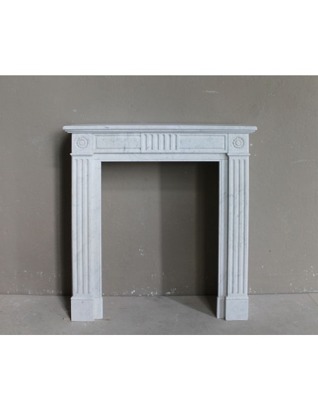Grazioso camino antico neoclassico di piccola taglia in marmo bianco con dettagli scultorei floreali molto eleganti.