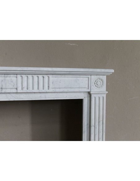 Grazioso camino antico neoclassico di piccola taglia in marmo bianco con dettagli scultorei floreali molto eleganti.