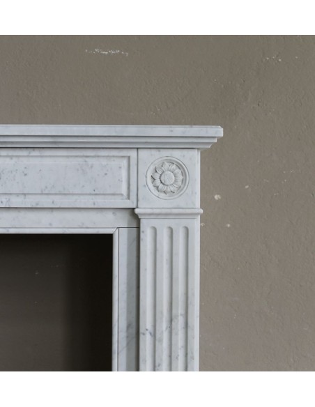 Grazioso camino antico neoclassico di piccola taglia in marmo bianco con dettagli scultorei floreali molto eleganti.