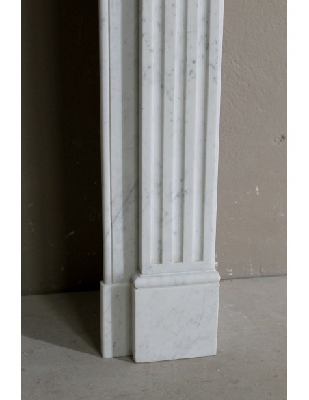 Grazioso camino antico neoclassico di piccola taglia in marmo bianco con dettagli scultorei floreali molto eleganti.