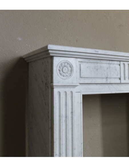 Grazioso camino antico neoclassico di piccola taglia in marmo bianco con dettagli scultorei floreali molto eleganti.