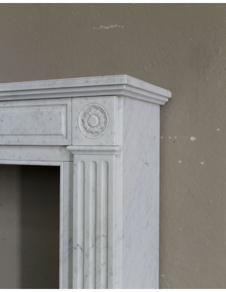 Grazioso camino antico neoclassico di piccola taglia in marmo bianco con dettagli scultorei floreali molto eleganti.