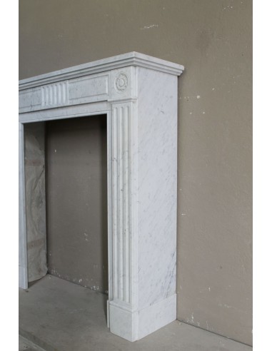 Grazioso camino antico neoclassico di piccola taglia in marmo bianco con dettagli scultorei floreali molto eleganti.