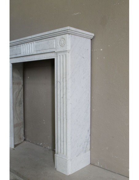 Grazioso camino antico neoclassico di piccola taglia in marmo bianco con dettagli scultorei floreali molto eleganti.