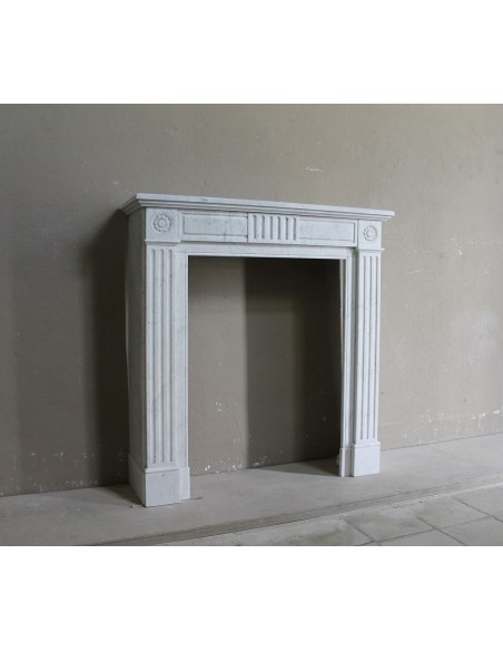 Grazioso camino antico neoclassico di piccola taglia in marmo bianco con dettagli scultorei floreali molto eleganti.