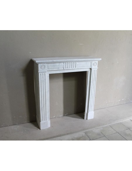 Grazioso camino antico neoclassico di piccola taglia in marmo bianco con dettagli scultorei floreali molto eleganti.