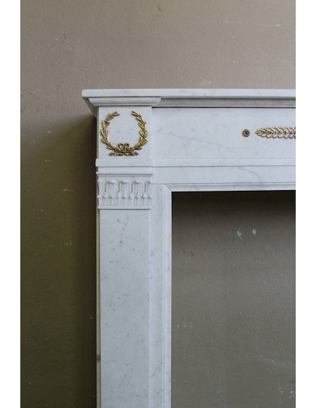 Camino antico neoclassico scolpito in marmo Bianco Carrara con inserti in bronzo dorato raffiguranti foglie d'ulivo e leoni