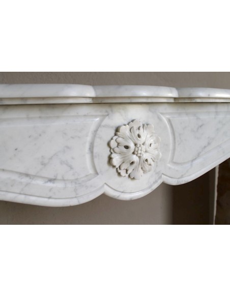 Caminetto antico barocco "Pompadour" scolpito in marmo bianco Carrara recante la scultura di una rosa al centro del frontale.