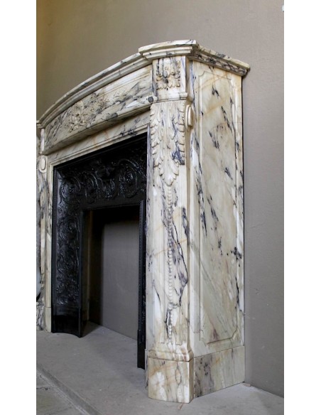 Camino neoclassico in marmo Statuario venato con toni dal bianco al beige al viola, provvisto di controcuore in ghisa d'origine.