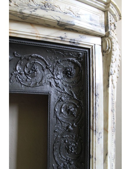 Camino neoclassico in marmo Statuario venato con toni dal bianco al beige al viola, provvisto di controcuore in ghisa d'origine.