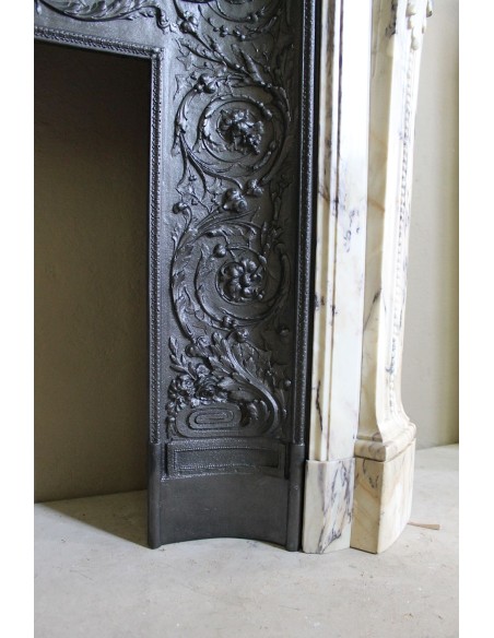 Camino neoclassico in marmo Statuario venato con toni dal bianco al beige al viola, provvisto di controcuore in ghisa d'origine.