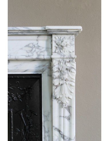 Camino neoclassico "Trois Fleurs" in marmo bianco venato Arabescato, provvisto di controcuore in ghisa artistica.