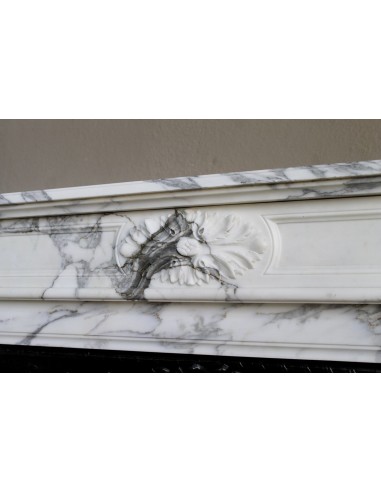 Camino neoclassico "Trois Fleurs" in marmo bianco venato Arabescato, provvisto di controcuore in ghisa artistica.