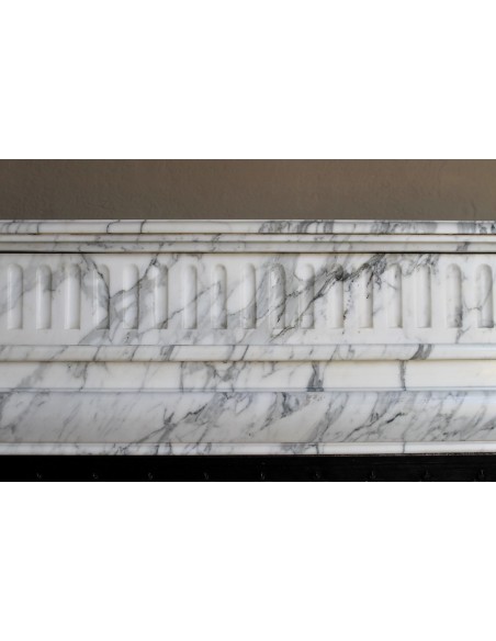 Camino antico "Boudin Haut" scolpito in marmo Calacatta bianco venato provvisto di controcuore in ghisa a "tapisserie".