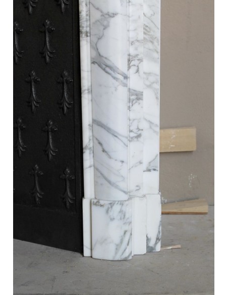 Camino antico "Boudin Haut" scolpito in marmo Calacatta bianco venato provvisto di controcuore in ghisa a "tapisserie".