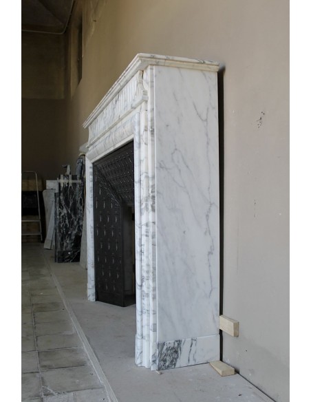 Camino antico "Boudin Haut" scolpito in marmo Calacatta bianco venato provvisto di controcuore in ghisa a "tapisserie".