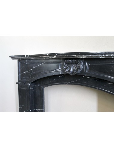 Camino antico di grandi dimensioni scolpito in nero Marquinia, con venature bianche a contrasto, a decoro barocco di conchiglia.