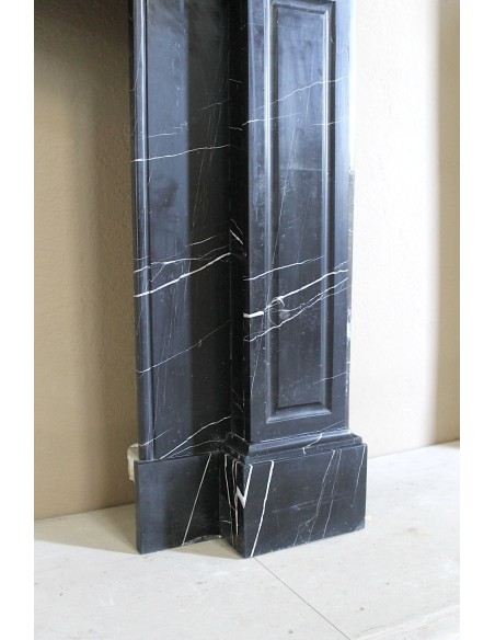 Camino antico di grandi dimensioni scolpito in nero Marquinia, con venature bianche a contrasto, a decoro barocco di conchiglia.