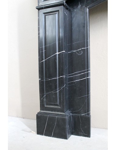 Camino antico di grandi dimensioni scolpito in nero Marquinia, con venature bianche a contrasto, a decoro barocco di conchiglia.