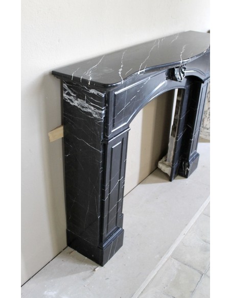 Camino antico di grandi dimensioni scolpito in nero Marquinia, con venature bianche a contrasto, a decoro barocco di conchiglia.