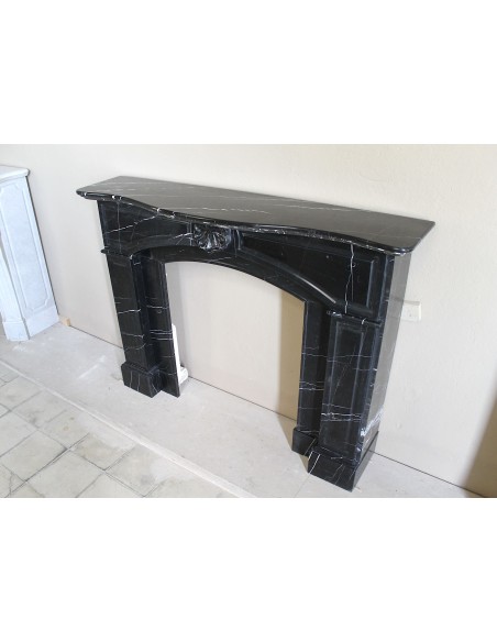 Camino antico di grandi dimensioni scolpito in nero Marquinia, con venature bianche a contrasto, a decoro barocco di conchiglia.