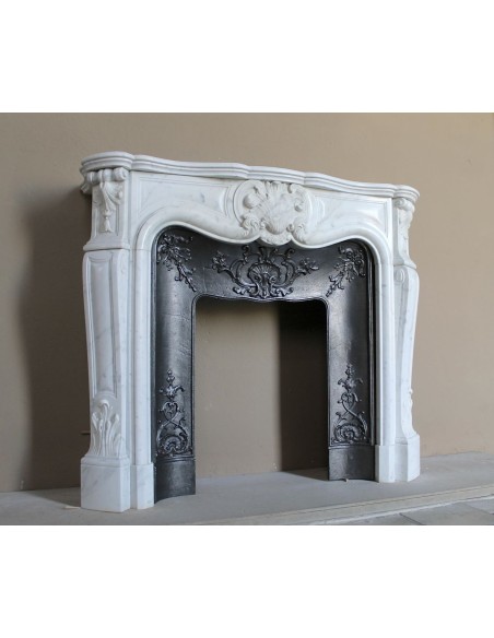 Caminetto barocco in marmo Bianco Carrara provvisto di controcuore in ghisa d'arte a decori floreali.