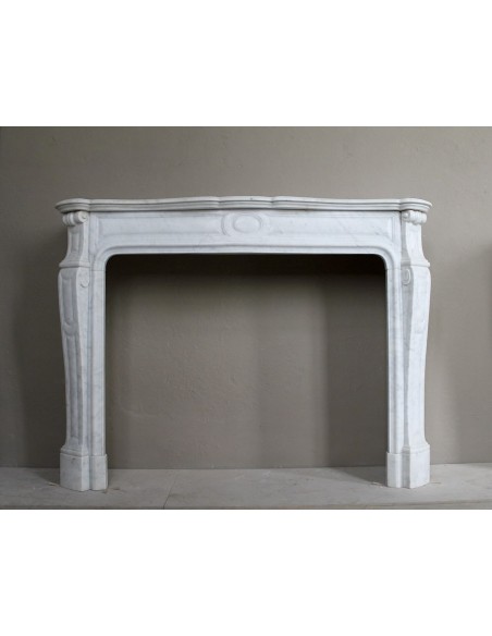 Cornice antica da camino "Pompadour" scolpita in candido marmo bianco Carrara e con bocche in bronzo decorate.