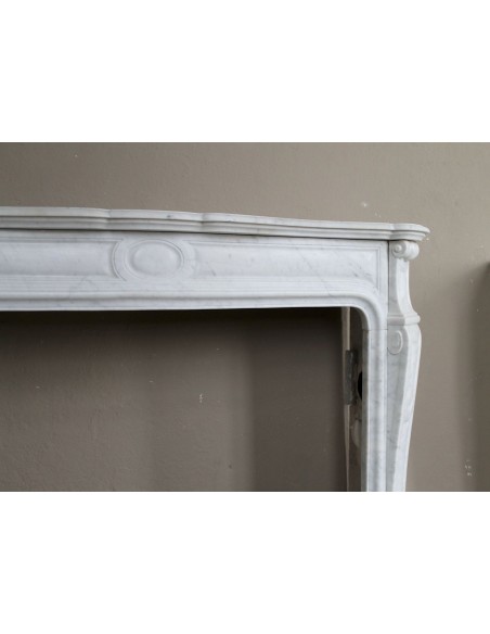 Cornice antica da camino "Pompadour" scolpita in candido marmo bianco Carrara e con bocche in bronzo decorate.