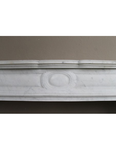 Cornice antica da camino "Pompadour" scolpita in candido marmo bianco Carrara e con bocche in bronzo decorate.