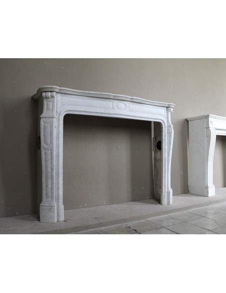 Cornice antica da camino "Pompadour" scolpita in candido marmo bianco Carrara e con bocche in bronzo decorate.