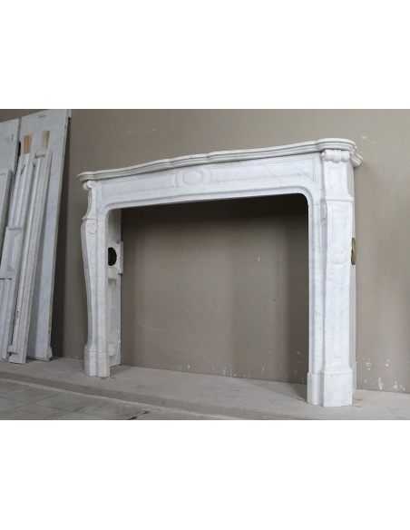 Cornice antica da camino "Pompadour" scolpita in candido marmo bianco Carrara e con bocche in bronzo decorate.