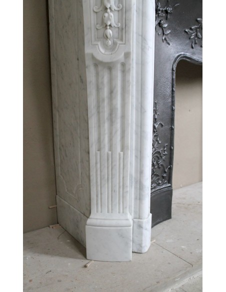 Camino barocco in marmo bianco Carrara con eleganti decori floreali provvisto di controcuore originale in ghisa artistica.