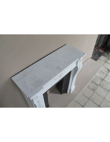 Camino neoclassico raro per la sua piccola misura ed il suo importante carico decorativo, in marmo bianco e con controcuore.