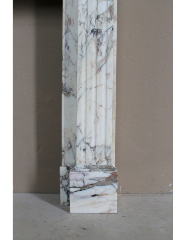 Camino neoclassico di piccola e graziosa taglia, scolpito in marmo Calacatta Oro Gold, con decori floreali.