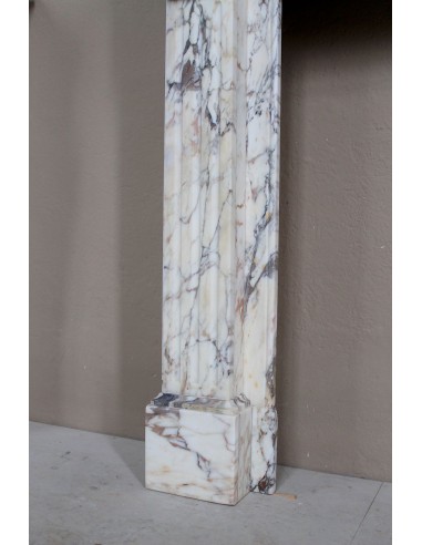 Camino neoclassico di piccola e graziosa taglia, scolpito in marmo Calacatta Oro Gold, con decori floreali.