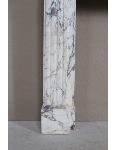 Camino neoclassico di piccola e graziosa taglia, scolpito in marmo Calacatta Oro Gold, con decori floreali.