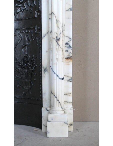 Camino neoclassico "Macaron" con elementi scultorei floreali, perlage, a colonna. Provvisto di controcuore in ghisa.