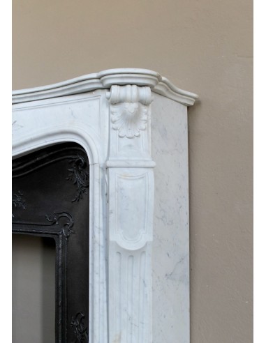 Elegante caminetto antico in marmo Bianco, di stile barocco, con elementi floreali, provvisto di controcuore in ghisa d'arte.