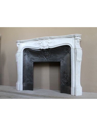 Elegante caminetto antico in marmo Bianco, di stile barocco, con elementi floreali, provvisto di controcuore in ghisa d'arte.