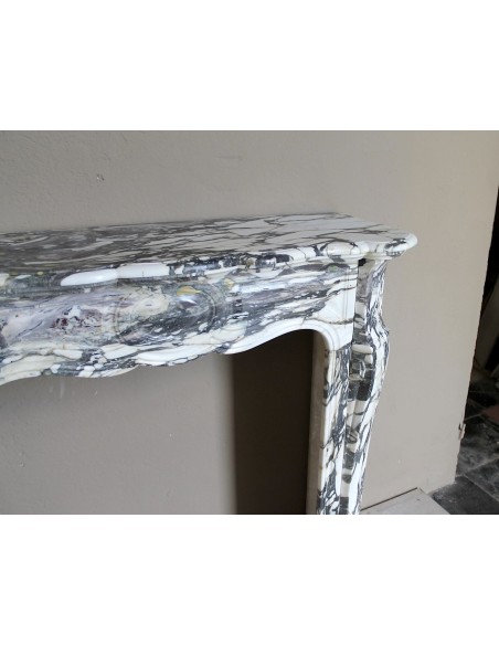 Piccolo camino barocco Pompadour in eccezionale marmo Breccia Medicea, con forti venature viola, verdi e oro su fondo bianco.