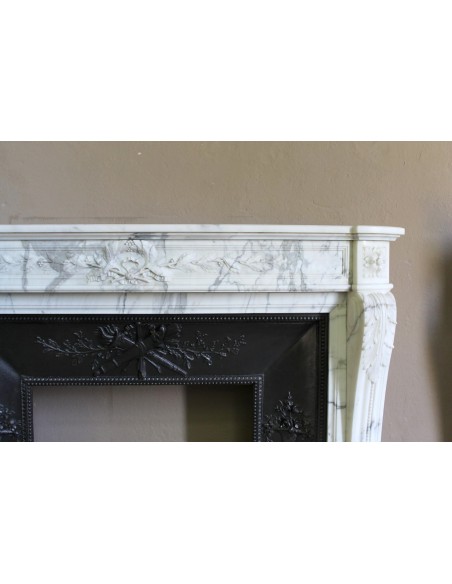 Camino antico neoclassico "Ramo d'ulivo" scolpito in marmo Bianco venato Arabescato provvisto di controcuore in ghisa d'arte.