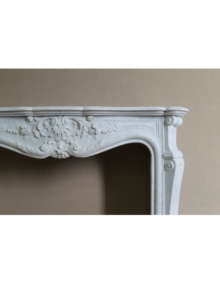 Elegante e ricercato camino in marmo bianco "Pied Galbé" con tripudio di elementi floreali scolpiti nel centro del frontale.