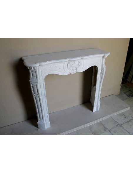 Camino antico barocco in marmo Bianco Carrara arricchito dalla scultura di una conchiglia al centro e riccioli sui capitelli.