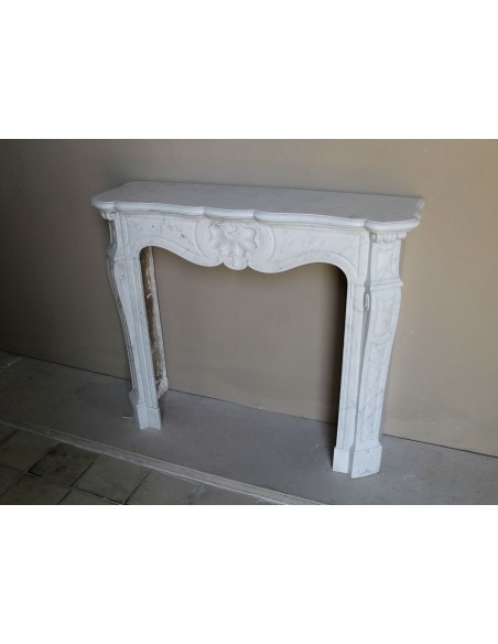 Camino antico barocco in marmo Bianco Carrara arricchito dalla scultura di una conchiglia al centro e riccioli sui capitelli.