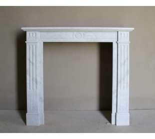 Caminetto Neoclassico "Marguerite" scolpito in marmo bianco Carrara, con decoro floreale al centro e elementi scanalati ai lati.