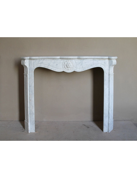 Caminetto antico barocco "Pompadour" scolpito in marmo bianco Carrara recante la scultura di una rosa al centro del frontale.