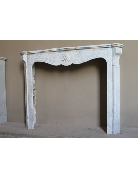 Caminetto antico barocco "Pompadour" scolpito in marmo bianco Carrara recante la scultura di una rosa al centro del frontale.