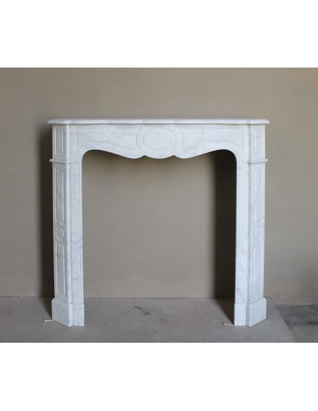 Caminetto antico Pompadour scolpito in marmo bianco dalle linee iconiche, d'un barocco leggero.