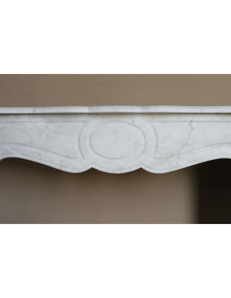 Caminetto antico Pompadour scolpito in marmo bianco dalle linee iconiche, d'un barocco leggero.