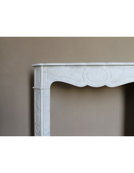 Caminetto antico Pompadour scolpito in marmo bianco dalle linee iconiche, d'un barocco leggero.